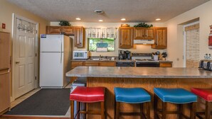 A kitchen with wooden cabinets, a white refrigerator, a microwave, a coffee maker, and a sink. - Golden Pond 2 Bedroom House (Swanton)