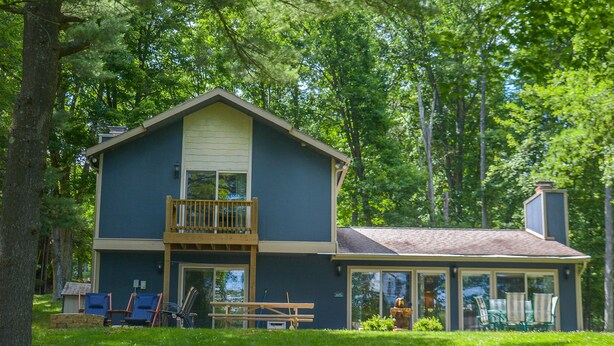 A two-story house with a balcony, a covered patio, and a fire hydrant in the yard. - Golden Pond 2 Bedroom House (Swanton)
