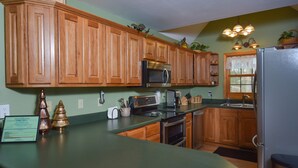 A kitchen with wooden cabinets, stainless steel appliances, and a green countertop.