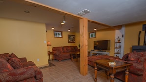 A living room with a sofa, a coffee table, and a TV. - All About Me 4 Bedroom House (McHenry)
