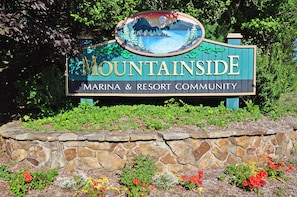 A sign for the Marina & Resort Community with a scenic view of mountains and a lake.