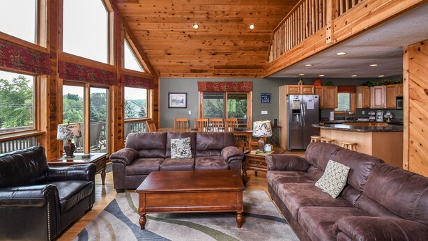 A spacious living room with leather sofas, a wooden coffee table, and large windows.