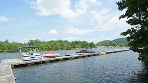 A dock with boats and a pier extending into a lake, surrounded by trees and hills.