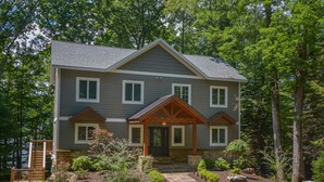 A two-story house with a stone foundation, a front porch, and a landscaped garden.