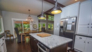 A modern kitchen with a marble countertop, stainless steel appliances, and a large island.