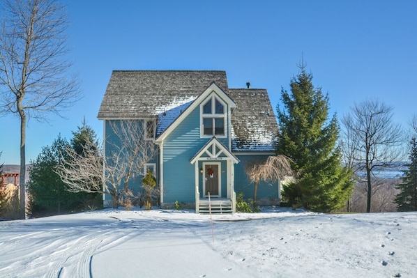 A two-story house with a steeply pitched roof and a front porch.