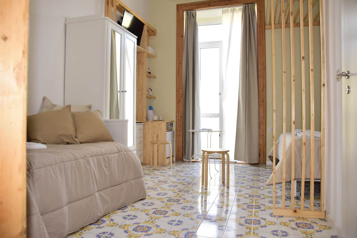 A bedroom with a bed, a wardrobe, a small table, and a chair.