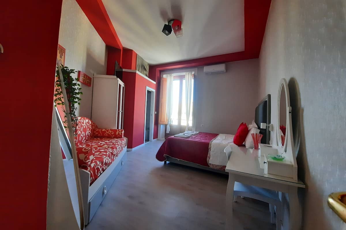 A room with a bed, a desk, a mirror, and a wardrobe.