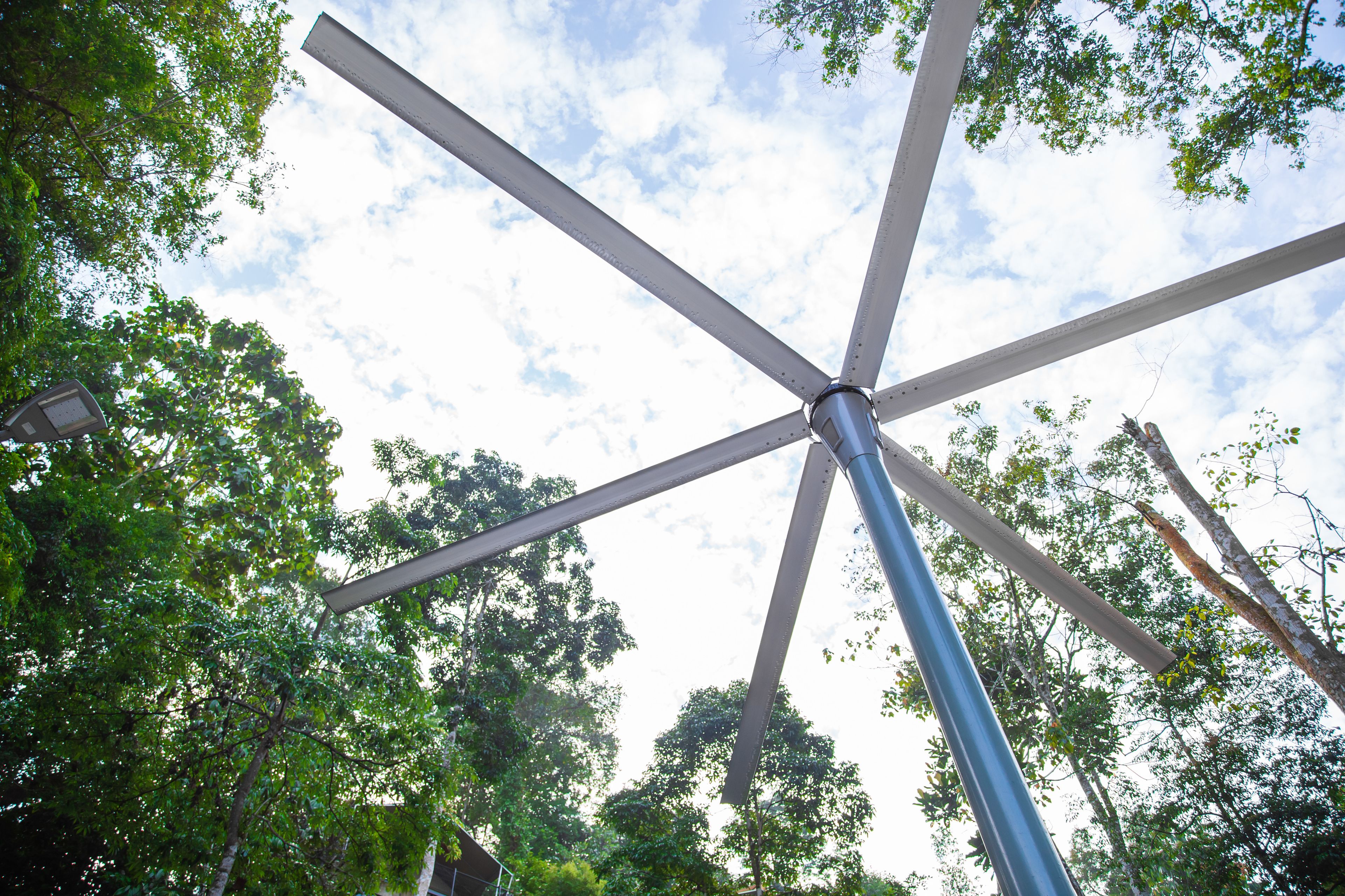 A metal structure with intersecting beams against a backdrop of trees and a partly cloudy sky.