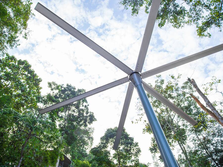 A metal structure with intersecting beams against a backdrop of trees and a partly cloudy sky.