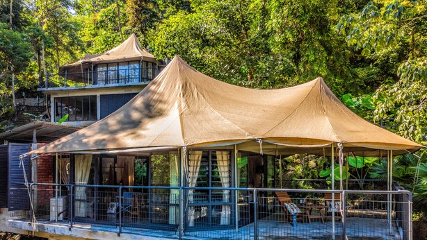 A two-story building with a covered outdoor area featuring a railing and a glass enclosure. - Boulder Valley (George Town)
