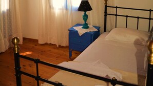 Une chambre à coucher avec un lit, des rideaux, une table de chevet et une lampe.