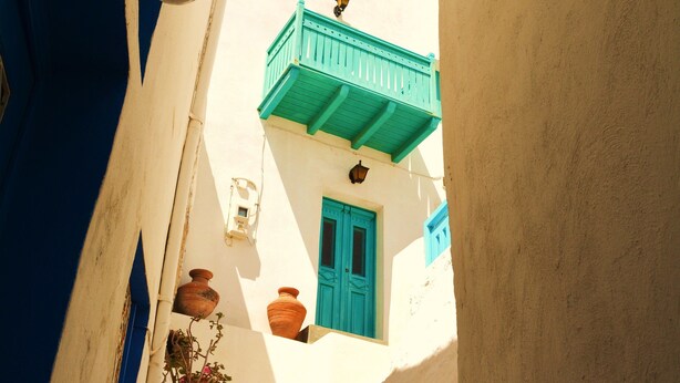 Un escalier étroit mène à un immeuble dont la porte est bleue et qui possède un balcon vert.