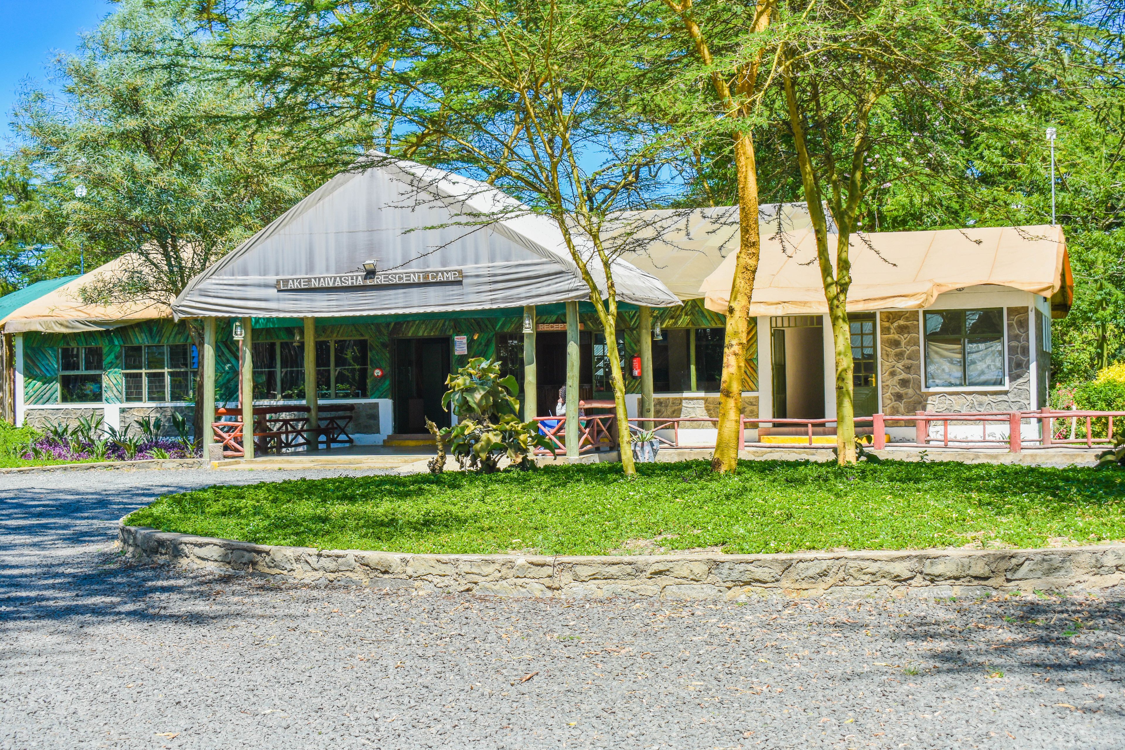 A lodge with a covered outdoor seating area, a stone building, and a sign reading "Lake Navaspa Resort Camp".