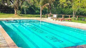 Una piscina rectangular con un deck de azulejos alrededor.
