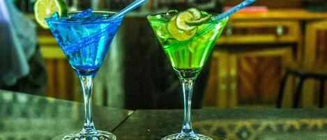 Two cocktails on a bar counter with a blurred background.