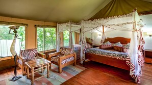 Una habitación con una cama, una mesa de madera y una silla, todo con ropa de cama estilo cebra.