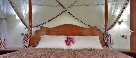 Una cama con dosel con dosel, ropa de cama con estampado de cebra, cabecera de madera y cortinas a rayas.