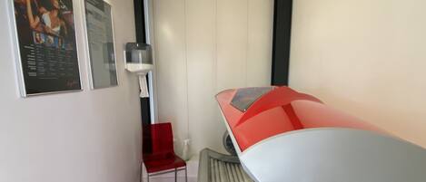 A modern hotel room with a bed, a red chair, a small table, and a poster on the wall.