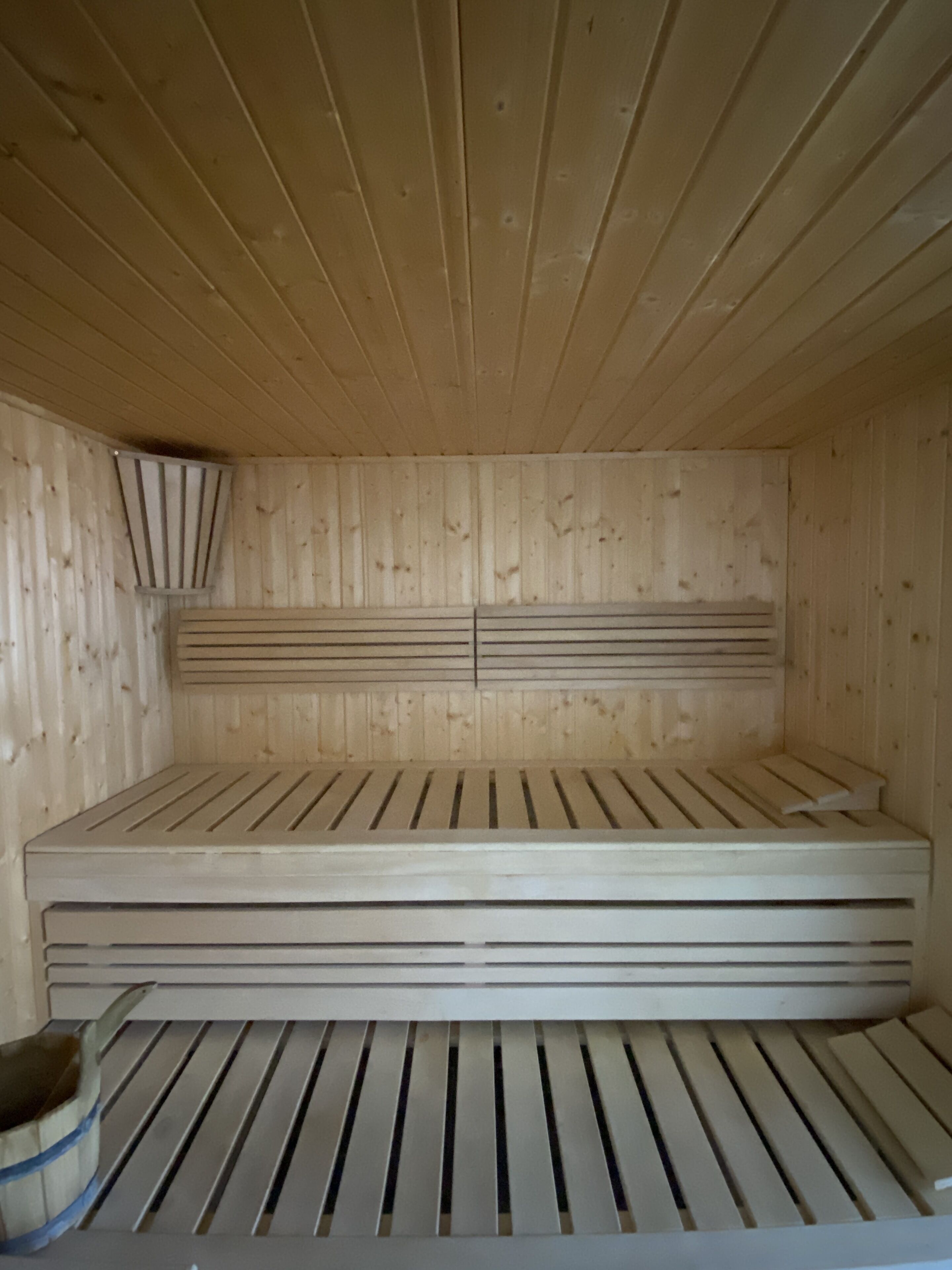 A sauna room with wooden walls and slatted flooring.