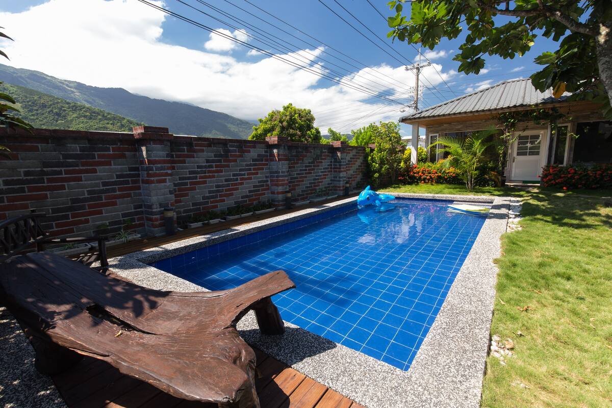 A swimming pool with a tiled deck, surrounded by a brick wall and a wooden deck.