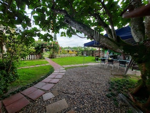 A garden pathway leading to a seating area with tables and chairs, surrounded by greenery and a white fence. - Gengmengyuan B&B (Shoufeng)