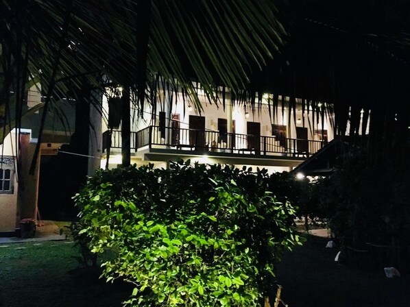 Un edificio con balcón y un jardín bien cuidado.