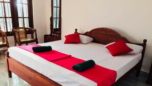 Una cama bien hecha con estructura de madera, ropa de cama blanca y detalles en rojo.