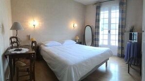 A neatly arranged bedroom with a bed, bedside lamps, a mirror, and a table with a lamp. - Mimat'hôtel (Mende)