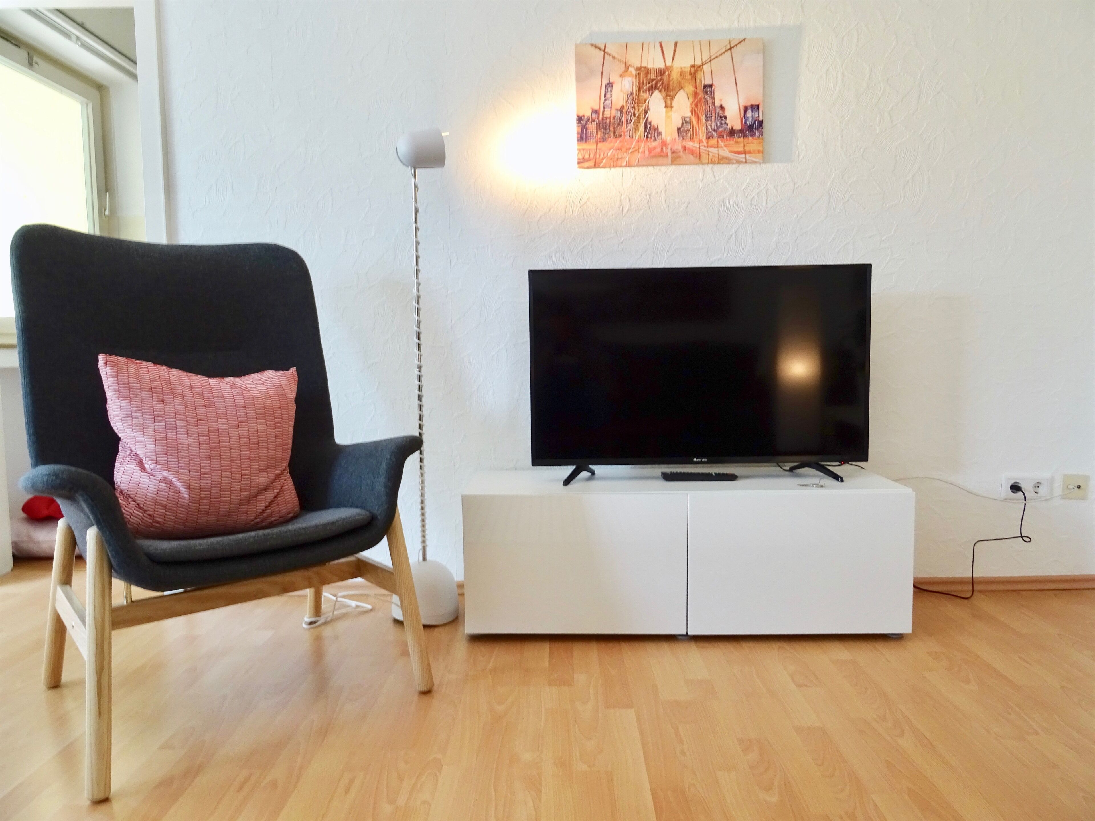 A modern living room with a black chair, a white entertainment unit, and a flat-screen TV.