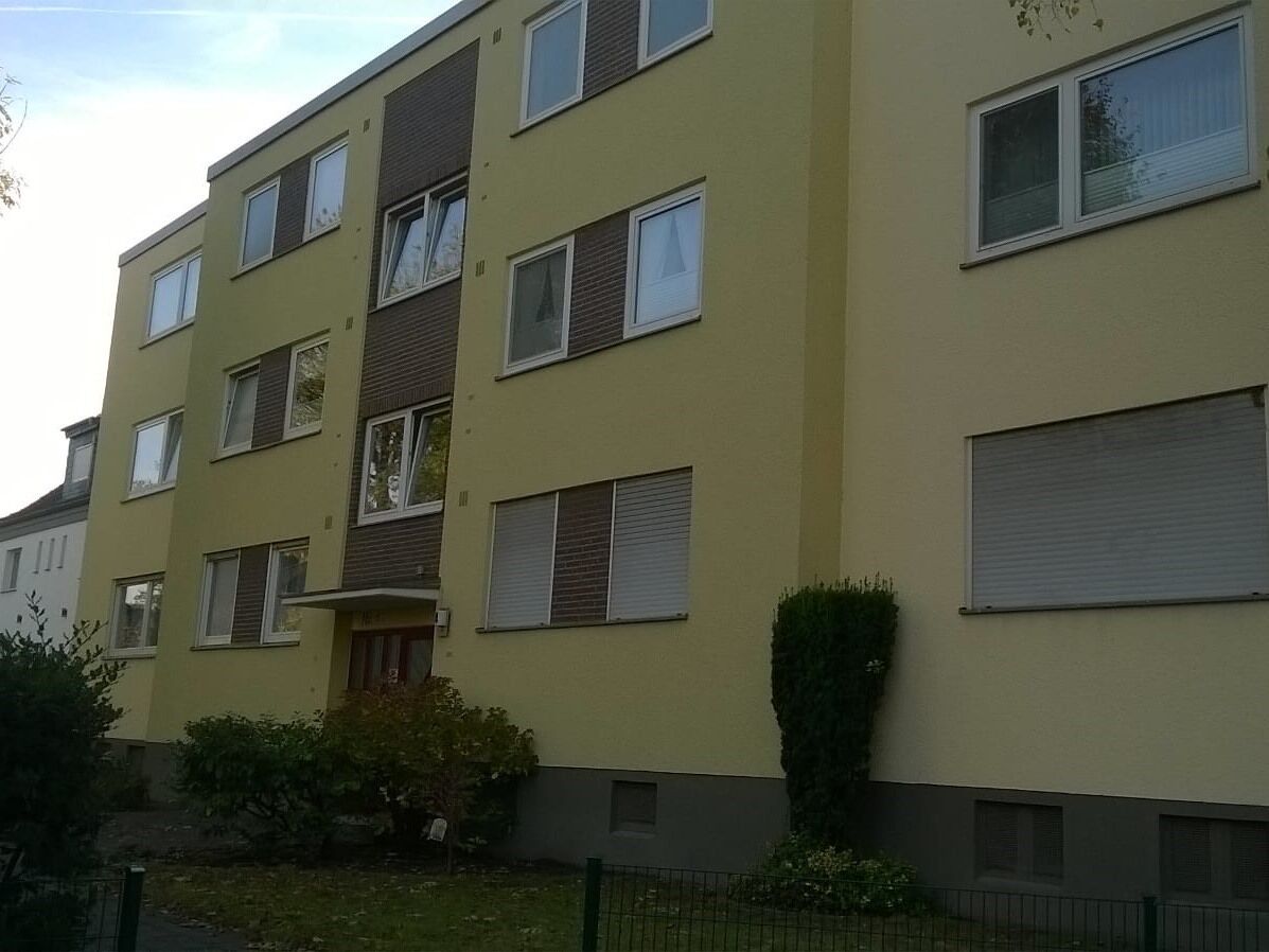 Un edificio residencial de varios pisos con fachada plana, numerosas ventanas y un pequeño porche delantero.
