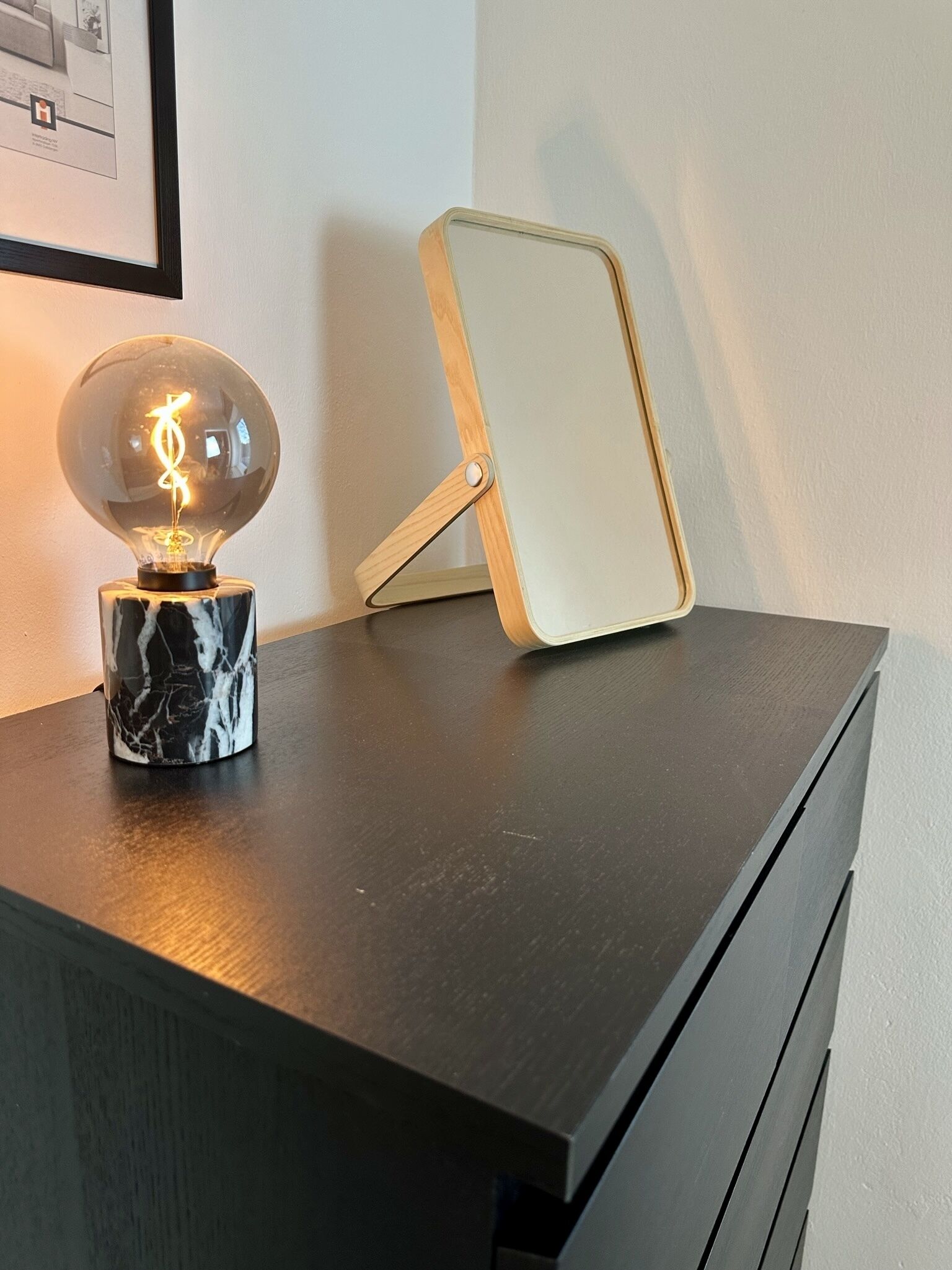 Een bureau met een marmeren voet, een gloeilamp en een spiegel.