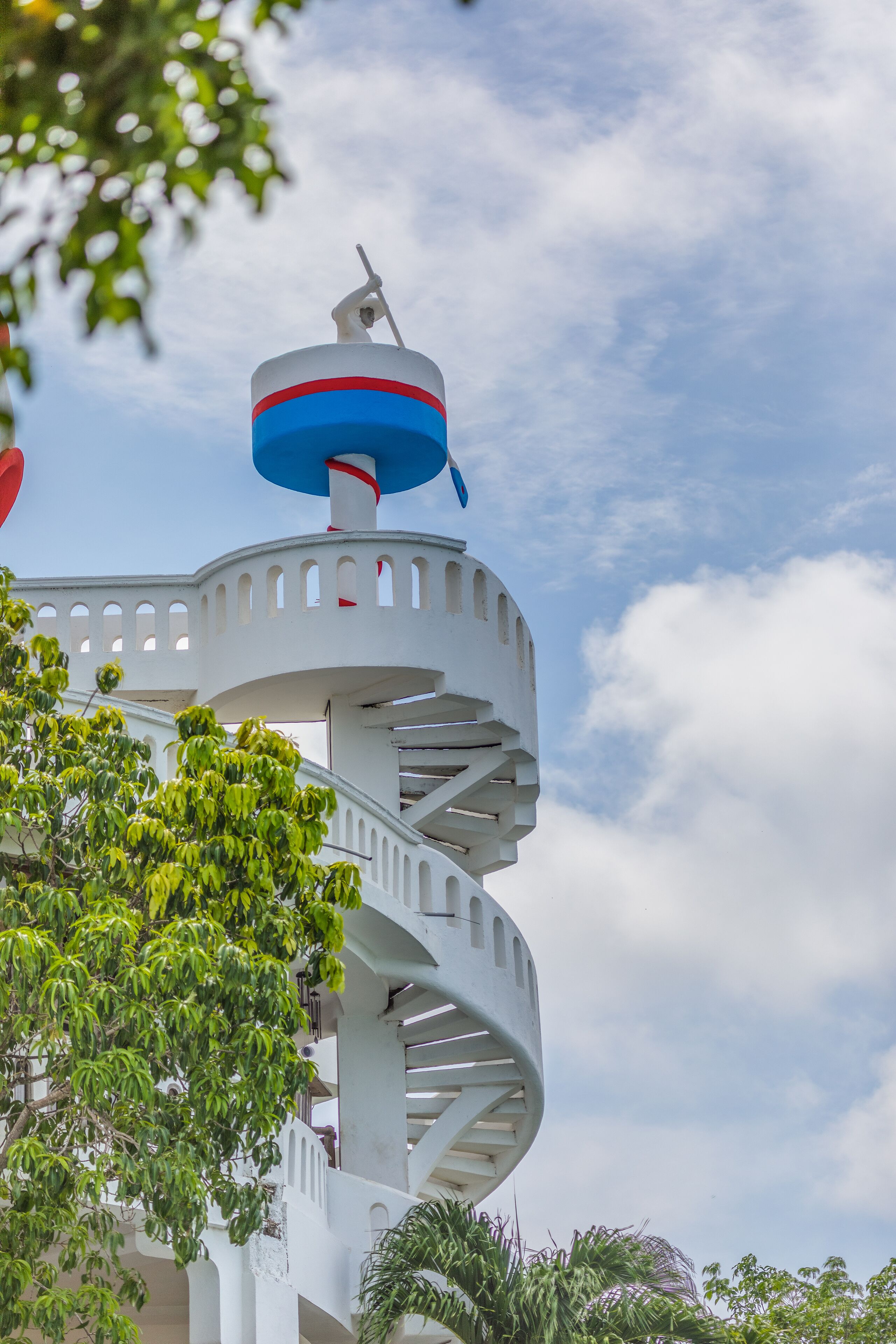 Una escalera en espiral blanca con un elemento decorativo rojo y azul en la parte superior.