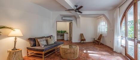 A spacious living area with a sofa, a round wicker coffee table, and a ceiling fan.