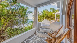A balcony with stone steps and wooden chairs, overlooking a lush garden and the sea. - Nosara Beach Hotel (Nosara)