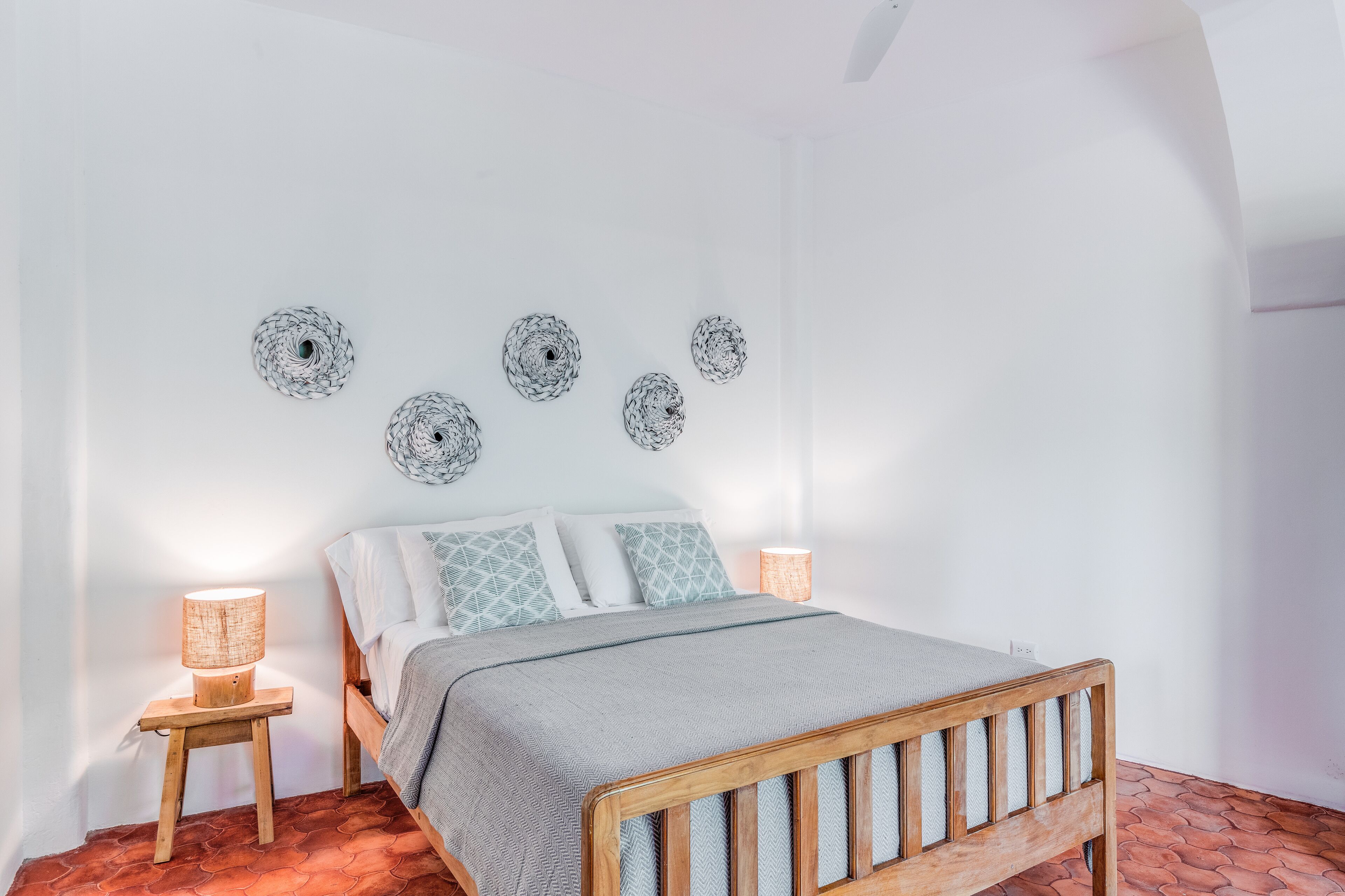 A bedroom with a wooden bed, a nightstand with a lamp, and decorative wall art.