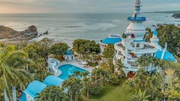 A resort with a large pool, multiple blue-roofed structures, and a view of the ocean. - Nosara Beach Hotel (Nosara)