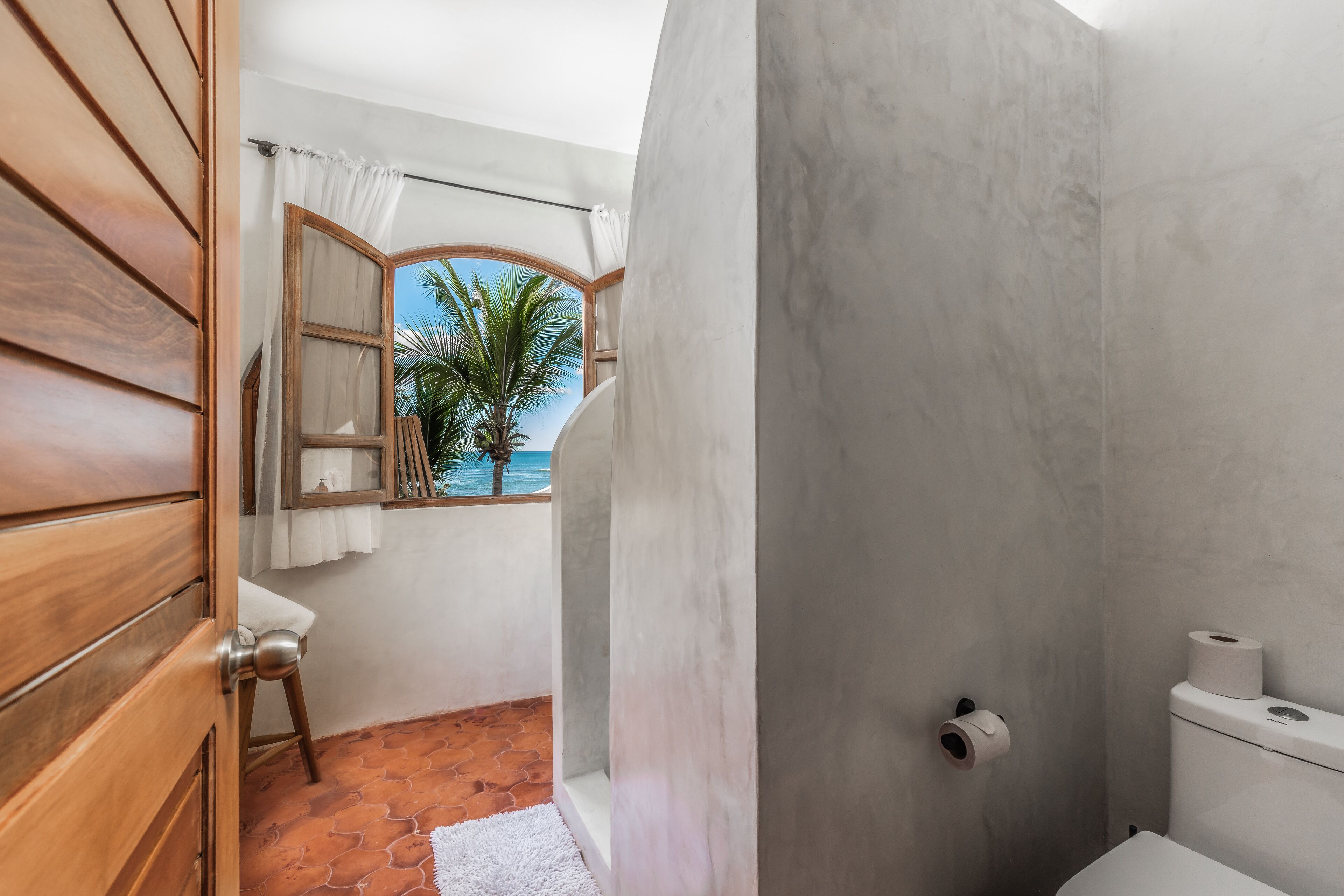 Un baño con vistas a la playa, un inodoro y una zona de ducha.