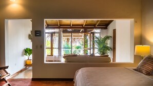 A bedroom with a large window, a bed, a bedside table, and a lamp. - Nosara Beach Hotel (Nosara)
