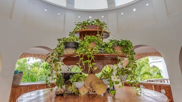 A round wooden table with multiple tiers of potted plants, surrounded by wooden chairs.