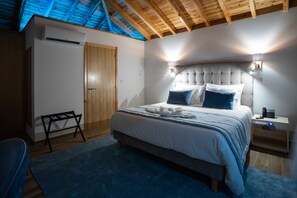 A bedroom with a bed, bedside tables, a bench, and a ceiling with wooden beams.