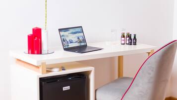 A modern workspace with a laptop, a refrigerator, and a chair.