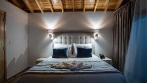 A hotel room with a large bed, a wooden ceiling, and two bedside lamps. - Quinta da Magnólia (Velas)