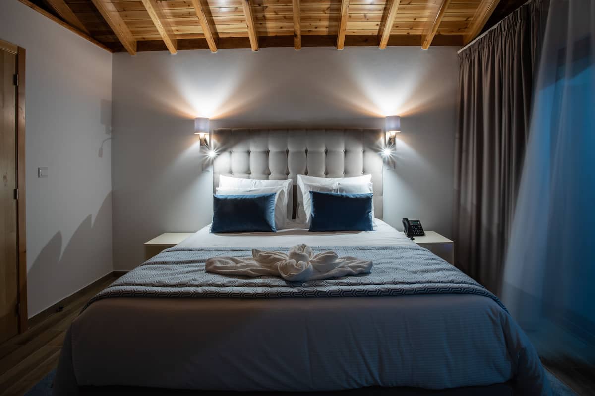 Ein Hotelzimmer mit einem großen Bett, einer Holzbalkendecke und zwei Nachttischlampen.