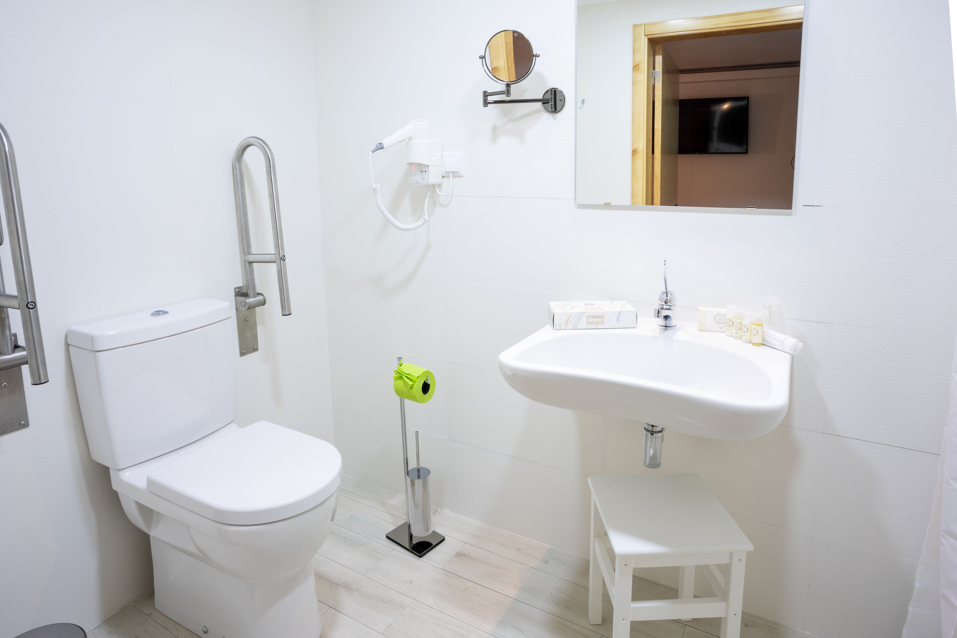 A modern bathroom with a toilet, sink, and a small stool.