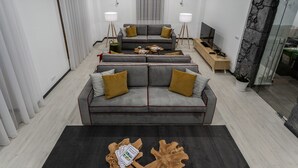 A modern living room with a grey sofa, two side tables, a coffee table, and a TV. - Quinta da Magnólia (Velas)