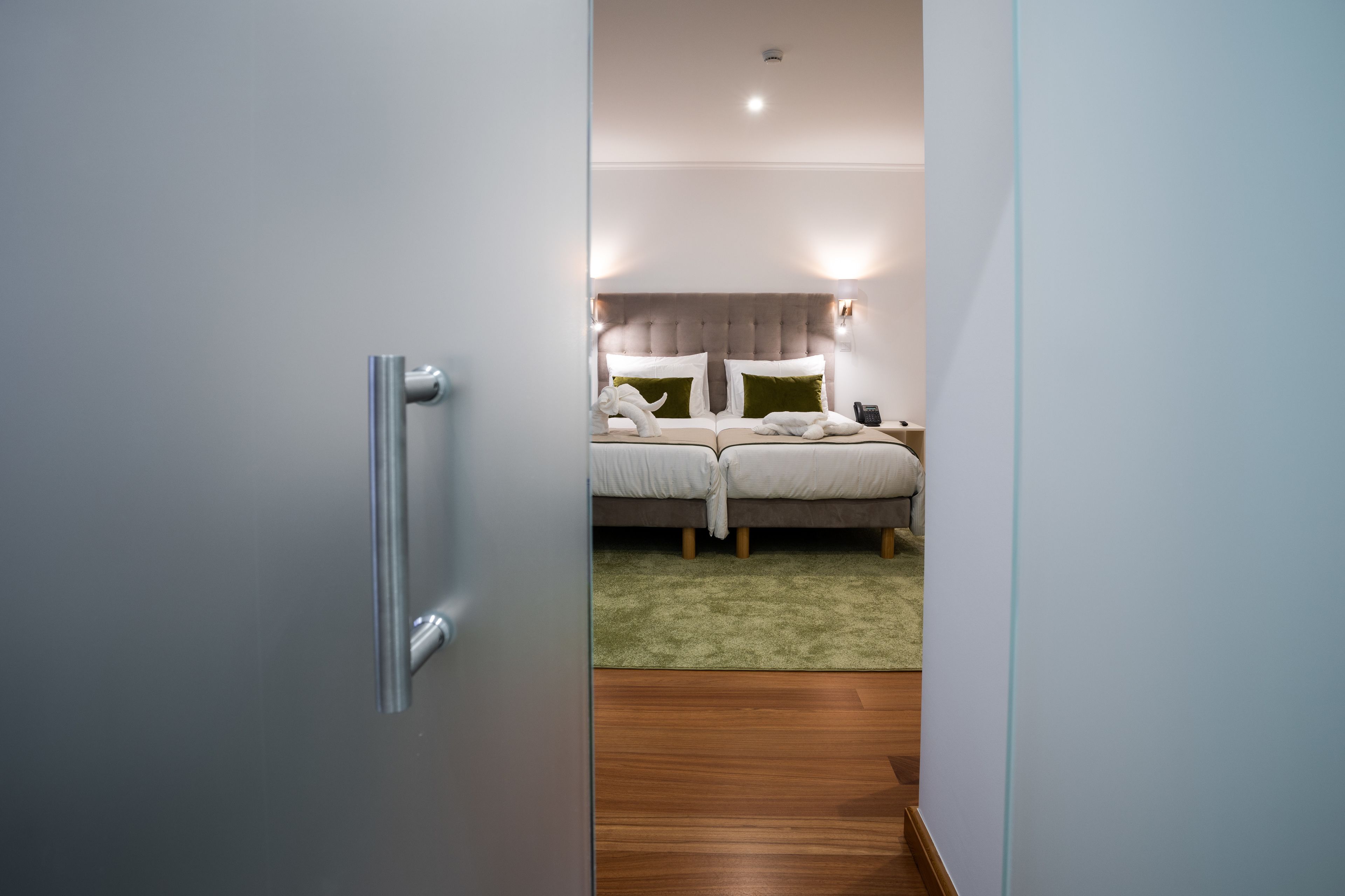A hotel room with a bed, bedside tables, and a green carpet.