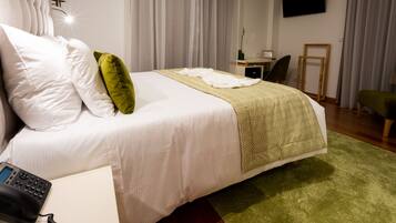 A hotel room with a bed, a desk, a chair, a TV, and a telephone.