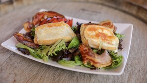 A sandwich on a white plate with lettuce and bacon, placed on a wooden table. - Hotel Macchie E Fiori (Pianotolli-Caldarello)