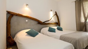 A room with two beds, each with a white mattress and teal pillows, and a wooden branch headboard. - Hotel Macchie E Fiori (Pianotolli-Caldarello)